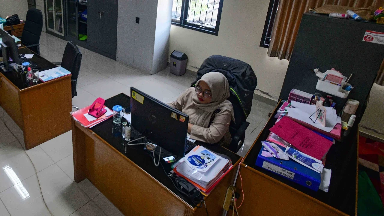 Staf bekerja di depan komputer dengan beberapa meja kursi yang kosong saat penerapan work from home (WFH) bagi aparatur sipil negara (ASN)  di kantor Kecamatan Limo, Depok, Jumat (10/04/2026).
