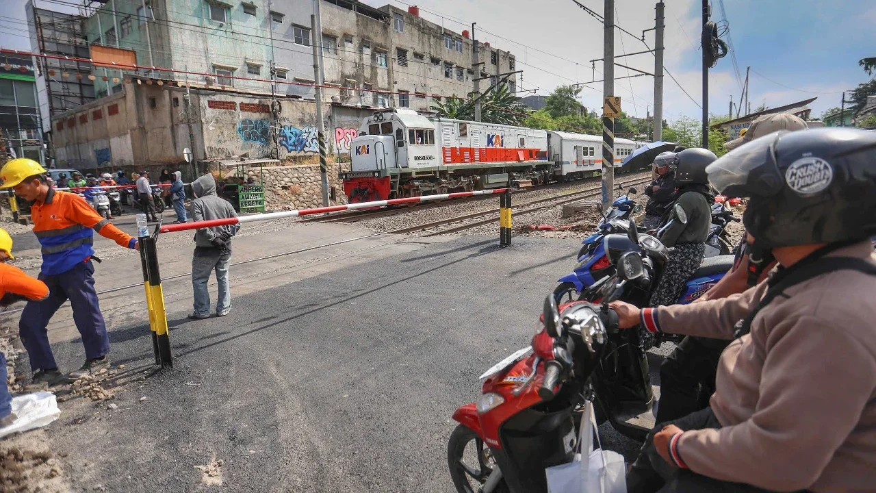 Pengendara bermotor menunggu kereta lewat pada palang pintu manual di perlintasan sebidang rel kereta api di Jalan Ampera, Bekasi, Jawa Barat, Kamis (30/04/2026).