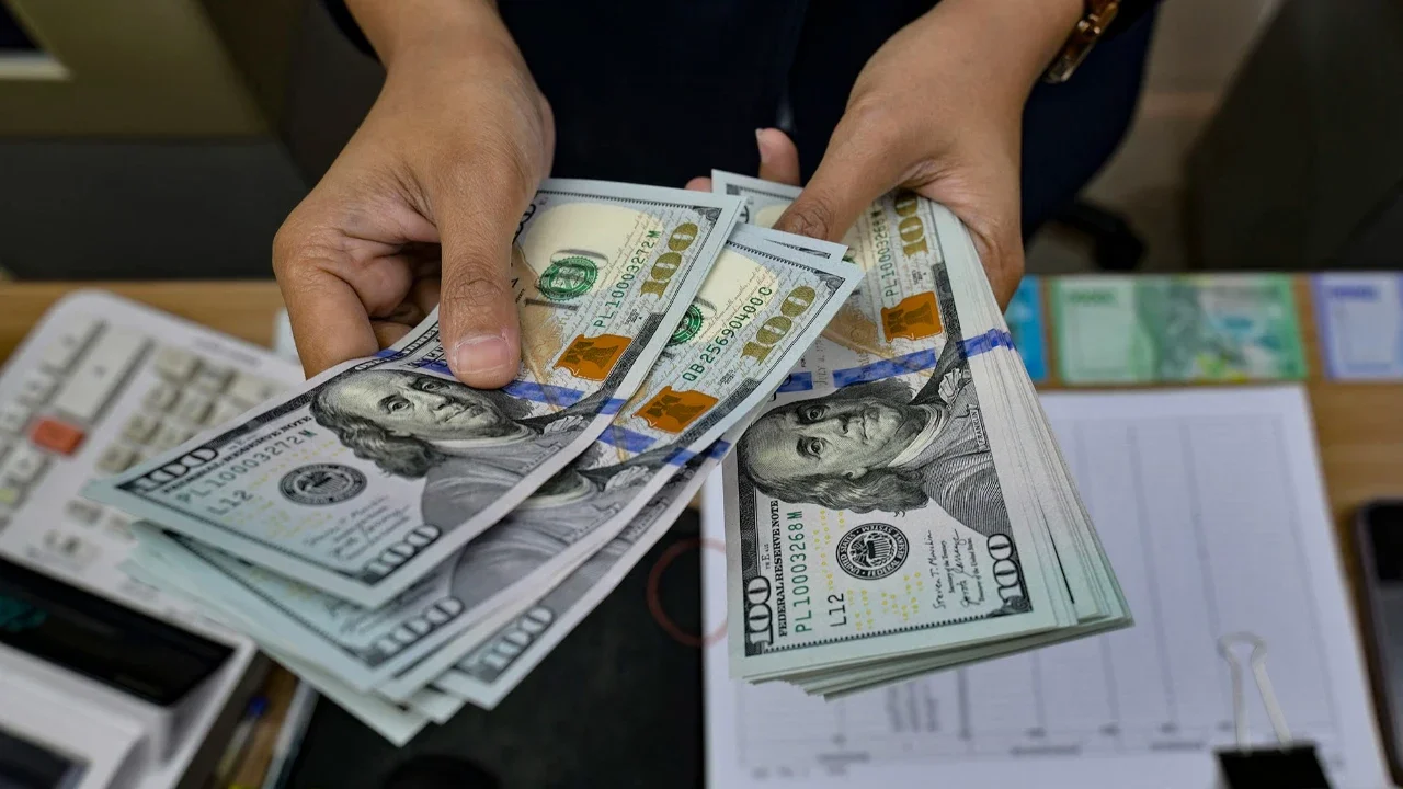Seorang penukar uang menghitung uang kertas Dolar AS di kantor penukaran uang di Jakarta,  Selasa (12/05/2026).