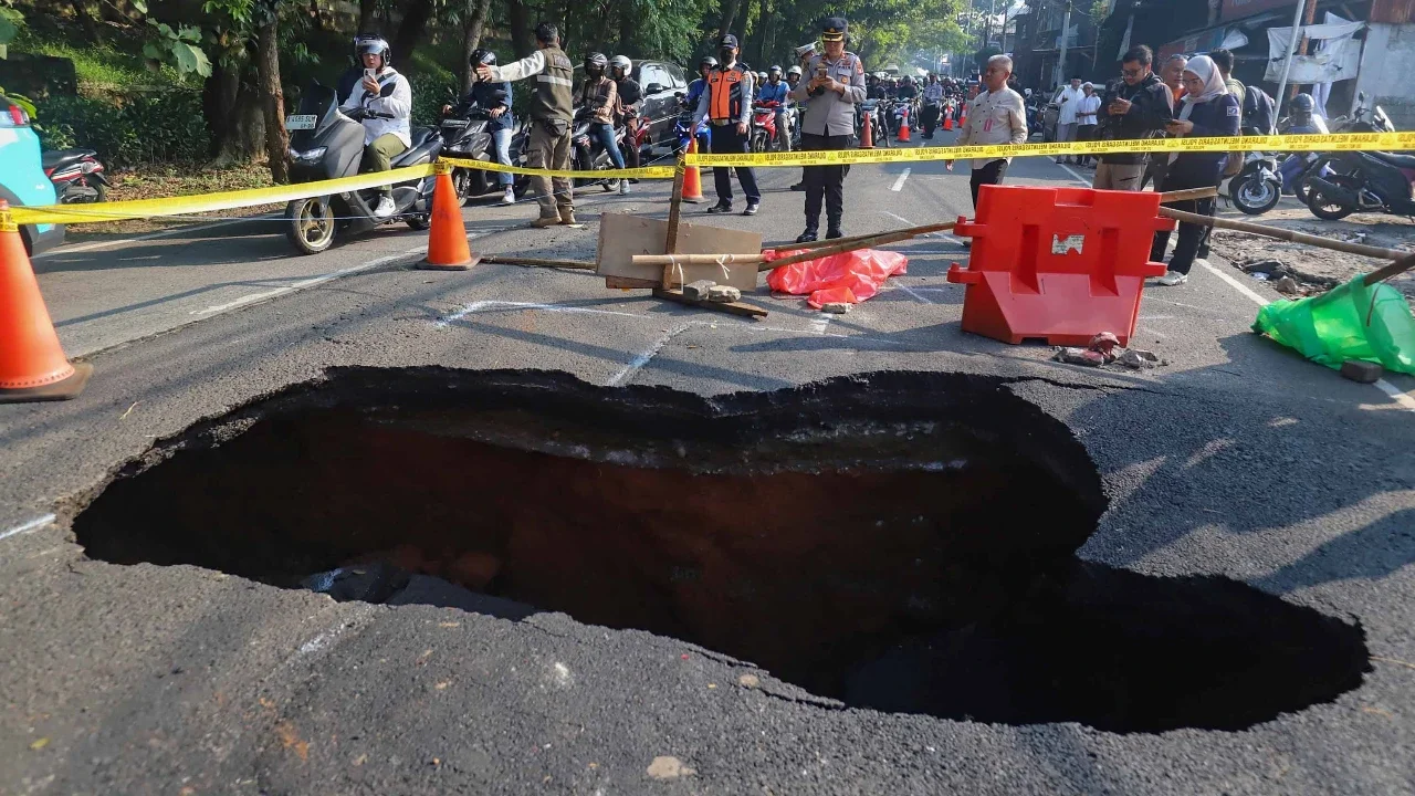 Pengendara bermotor melintas pada jalan yang ditutup sebagian  akibat jalan yang amblas di Jalan Raya Lenteng Agung, Jakarta Selatan, Jumat (29/5/2026).