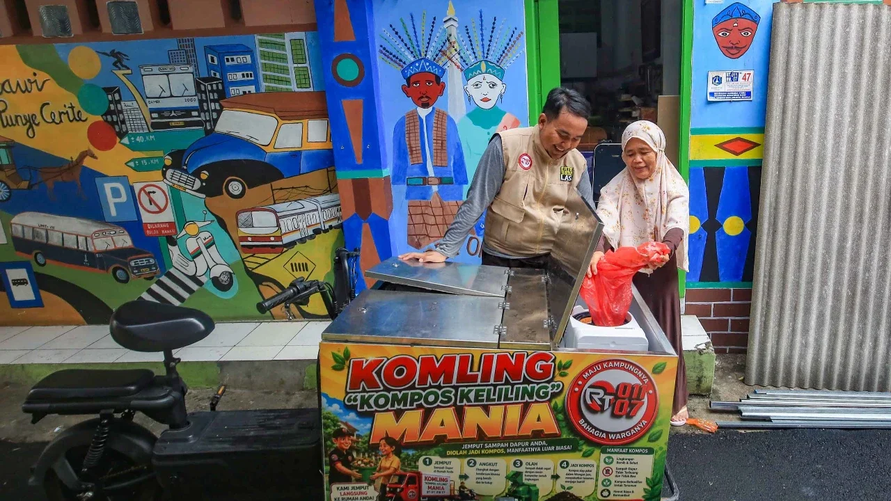Petugas melayani warga yang membuang sampah organik pada gerobak listrik Komling (kompos keliling) di Rt  11/ 07, Gandarai Utara, Jakarta, Minggu (28/06/2026).