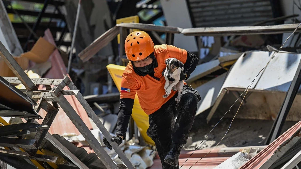 Petugas penyelamat dan seekor anjing pelacak melakukan operasi pencarian dan penyelamatan di lokasi bangunan yang runtuh setelah gempa bumi berkek magnitude 7,8 di Kota General Santos,  Filipina, Selasa (09/06/2026).