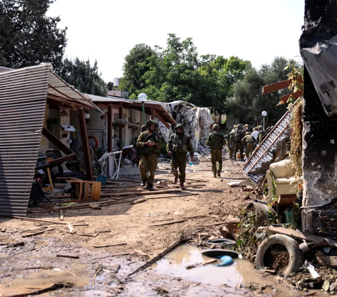 Tentara Israel berjalan melewati sisa-sisa kawasan pemukiman Yahudi di Kibbutz Kfar Aza, di Israel selatan pada (10/101/2023).<br><br>Kibbutz Kfar Aza menjadi salah satu wilayah terparah diserang roket Hamas.
