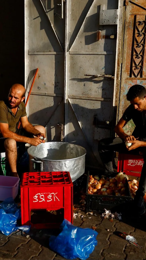 Dua pria Palestina di Khan Younis terlihat sibuk mengupas bawang saat akan diolah menjadi makanan untuk warga.