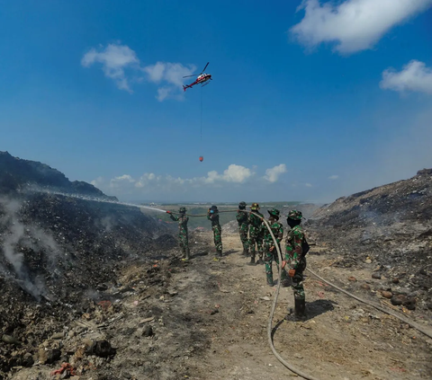 Anggota Raider 900/SBW TNI AD dan Helikopter Badan Nasional Penanggulangan Bencana (BNPB) saat berupaya memadamkan sisa api kebakaran sampah di Tempat Pembuangan Akhir (TPA) Regional Sarbagita Suwung, Denpasar, Bali, Jumat (20/10/2023).