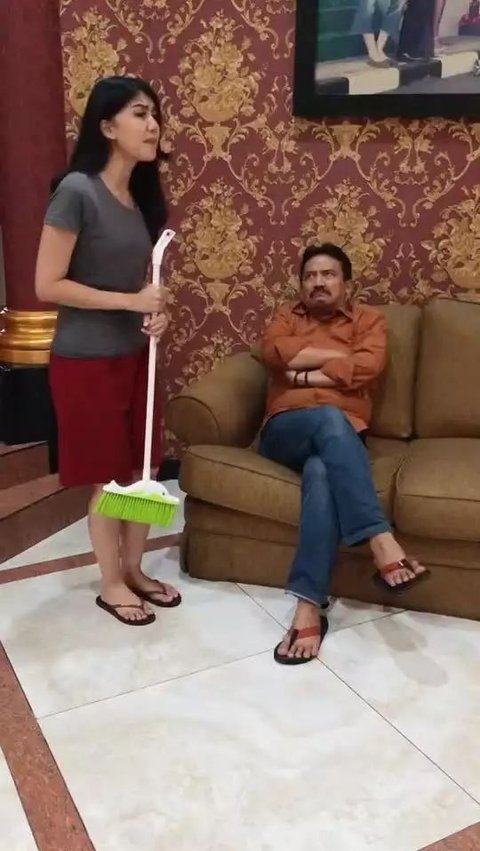 Ruang tamu berdinding merah-emas terlihat mewah dengan sofa cokelat yang ditempati oleh pemilik rumah, aktor Herdi Hidayat.