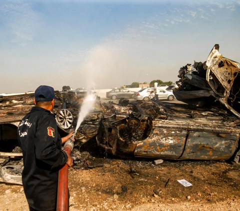 Anggota pertahanan sipil Mesir melakukan pendinginan pada kendaraan yang hangus terbakar di lokasi tabrakan beruntun yang melibatkan puluhan kendaraan di sepanjang jalan raya gurun Kairo-Alexandria pada 28 Oktober 2023. <br>