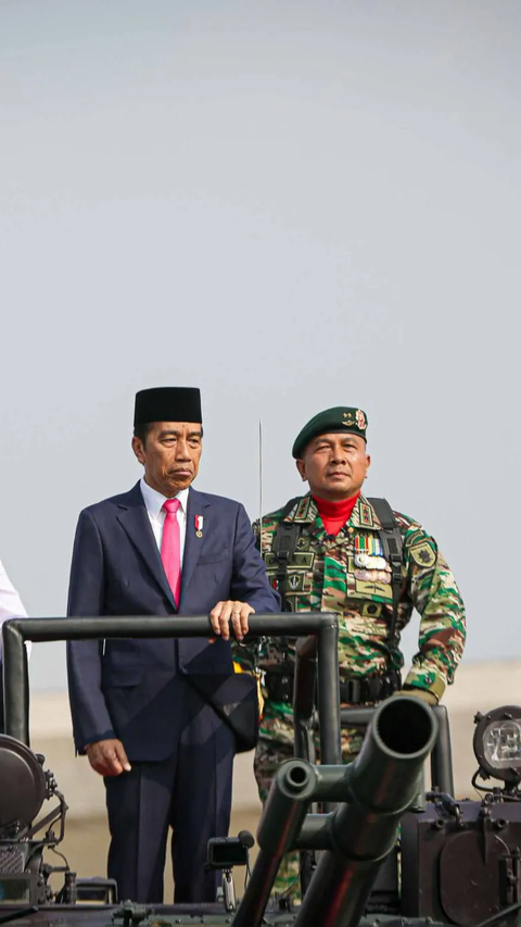 Jokowi terlihat mengenakan peci dan setelan jas hitam. Mantan Gubernur DKI Jakarta itu berdiri di atas tank BMP-3F Korps Marinir.