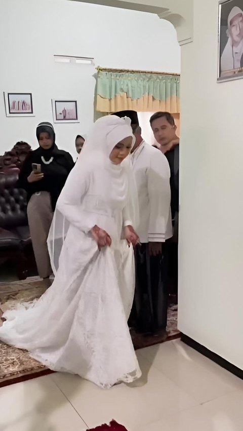The bride appears wearing a white Muslim bridal gown.