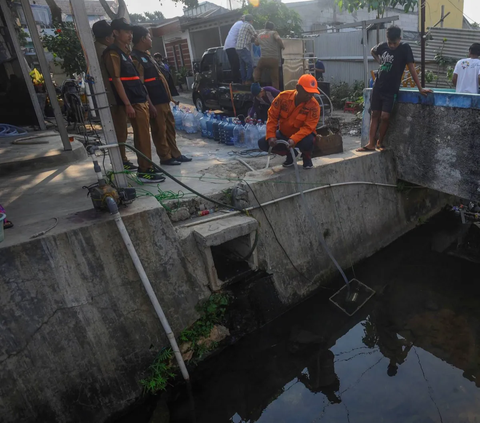 Petugas BPBD menggunakan selang saat mengambil sumber air dari sungai di lingkungan rumah warga di kawasan Kranggan, Tangerang Selatan.