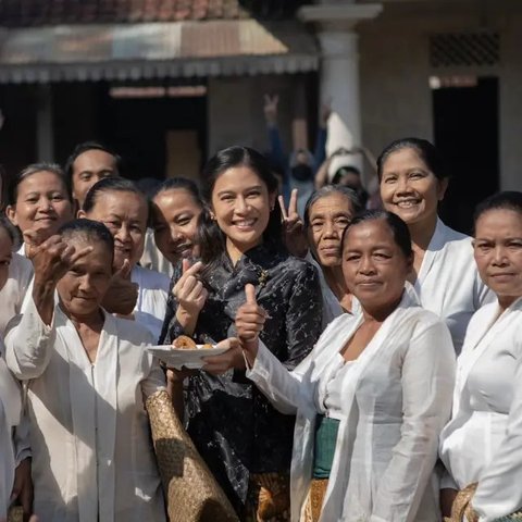 Dian Sastro mempesona dengan kebaya hitam klasiknya, berpose di antara ibu-ibu, menciptakan kesan kemewahan yang tak terbantahkan.