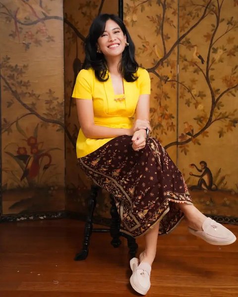 Dian Sastro memikat dengan kebaya kuning cerah dan kain batik merah bata yang cocok.