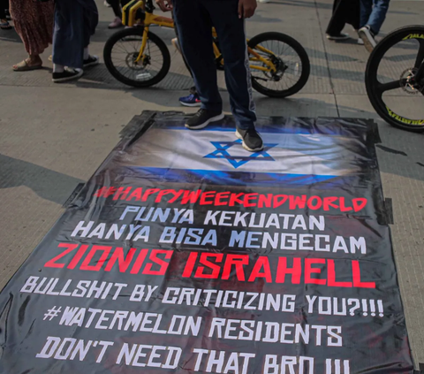 FOTO: Kutuk Serangan Pasukan Zionis, Warga Jakarta Ramai-Ramai Injak Spanduk Bendera Israel Saat CFD Sudirman-Thamrin