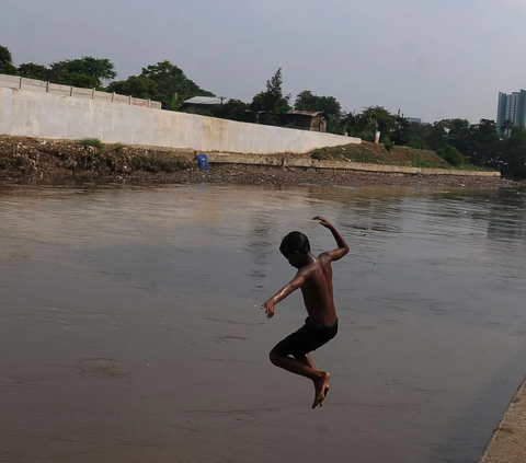 Sejumlah anak kembali dengan keceriaannya bermain di aliran kali Ciliwung yang sudah kembali dipenuhi air di kawasan Cawang, Jakarta, Kamis (16/11/2023). Sebelum kali ini nyaris kering akibat musim kemarau bulan lalu.<br>