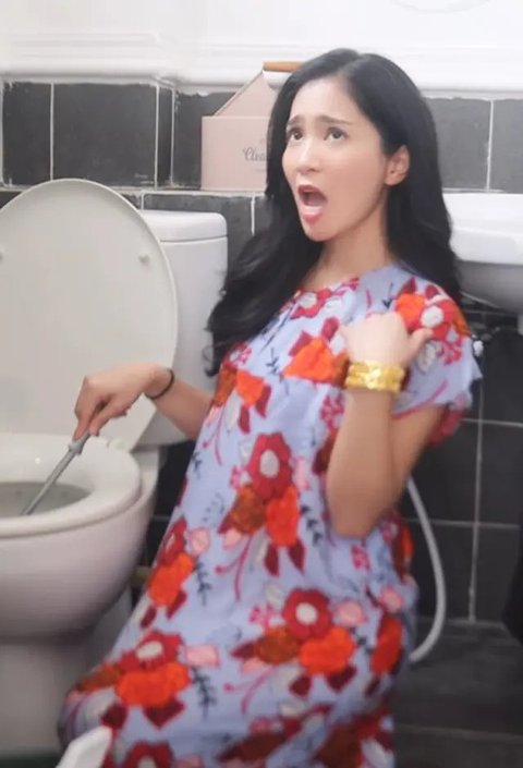 Tetap dengan daster dan ekspresi lucu, Bunga Zainal sedang membersihkan toilet.<br>
