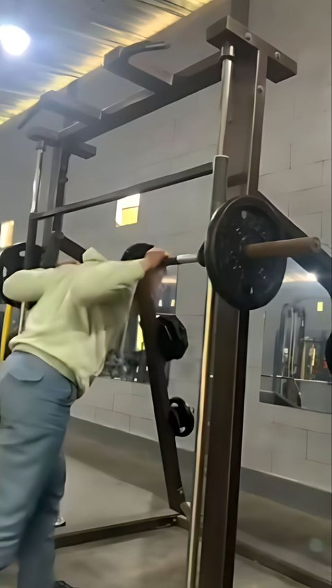 In the 13-second video, a young man can be seen preparing to do physical exercise using the Barbell Machine.