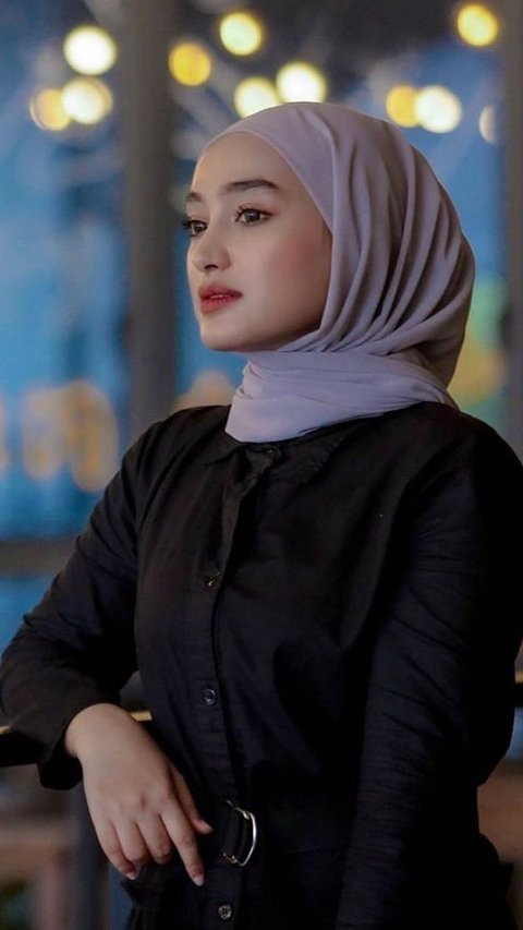 Santyka wears a gray hijab combined with a black outfit with a belt accent.