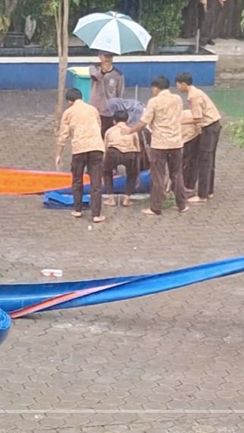 Di Tengah Rintik Hujan, Satpam ini Payungi Guru yang Sedang Salat, Aksinya Mulia Banget<br>