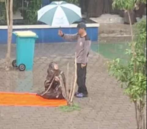 Di Tengah Rintik Hujan, Satpam ini Payungi Guru yang Sedang Salat, Aksinya Mulia Banget