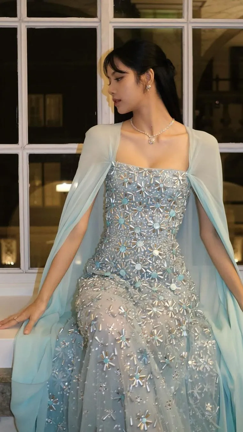 Lisa, selalu berani dalam gaya fashionnya, tampil memukau dengan gaun aquamarine dari Georges Hobeika, dilengkapi dengan gaun jubah anggun, platform emas metalik, dan kalung berlian.