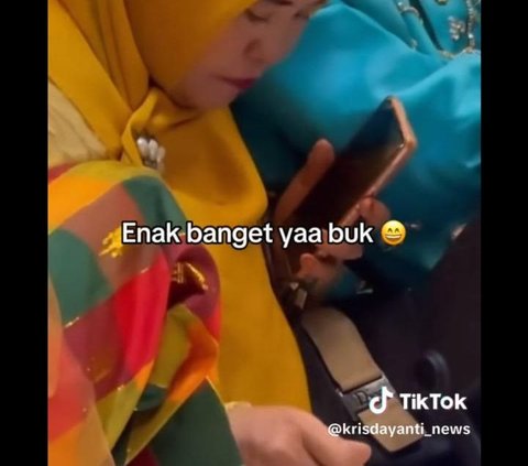 Ibu ini juga terlihat bisa membagi perhatiannya untuk makan, menonton Krisdayanti bernyanyi, sambil memegang <i>handphone</i> untuk merekam.