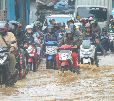 Pengendara menerobos banjir yang mengenangi Jalan Raya Bogor di depan Pasar Induk Kramat Jati, Jakarta, Kamis (30/11/2023). <br>
