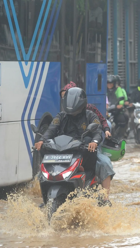 Seorang pengendara sepeda motor saat menerobos genangan banjir yang merendam Jalan Raya Bogor di depan Pasar Induk Kramat Jati.