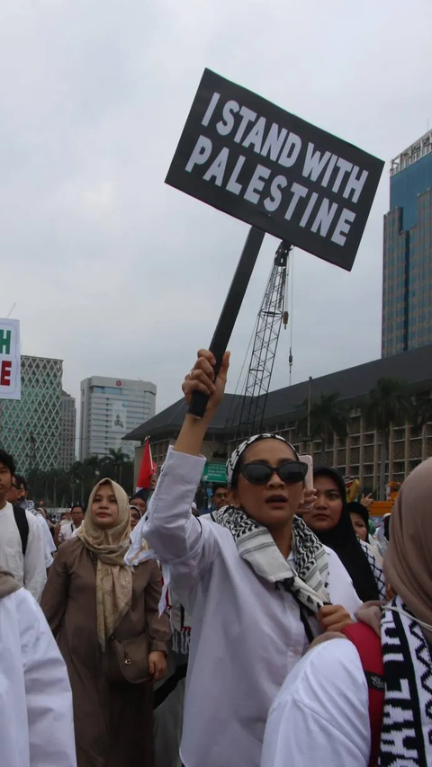 Seorang pengunjuk rasa menunjukkan poster saat aksi damai bela Palestia di kawasan Monas, Jakarta, Minggu (5/11/2023).