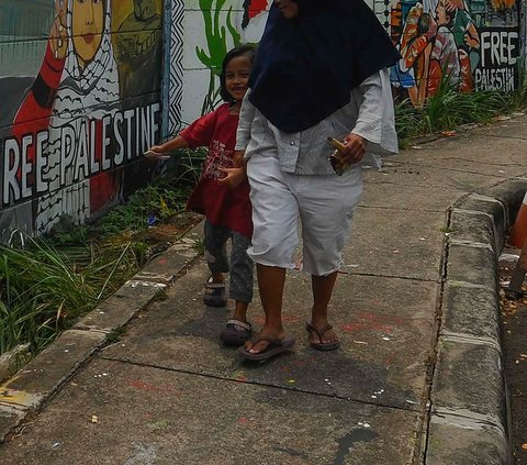 Warga melintas di depan mural dukungan untuk Palestina di Jalan Juanda, Kota Depok, Jawa Barat, pada Rabu (8/11/2023). Merdeka.com/Arie Basuki