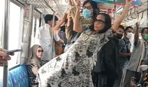 Menggunakan dress panjang dan kacamata hitam, dia dengan santai bergelantungan di depan penumpang lain.