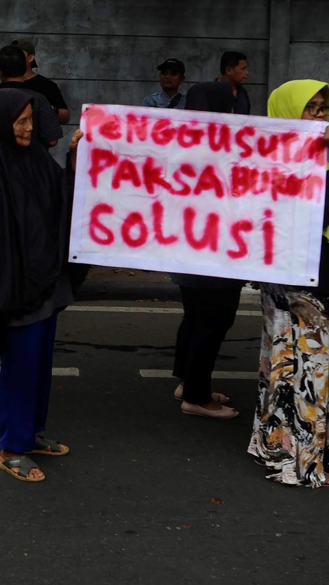 Demonstran ibu-ibu menunjukkan poster bertuliskan 