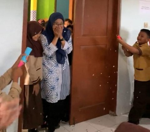 Saat masuk ke kelas, anak-anak pun mulai menembakkan confeti yang sejak tadi mereka pegang. Ibu guru kaget dan menunjukkan raut wajah bahagianya. 