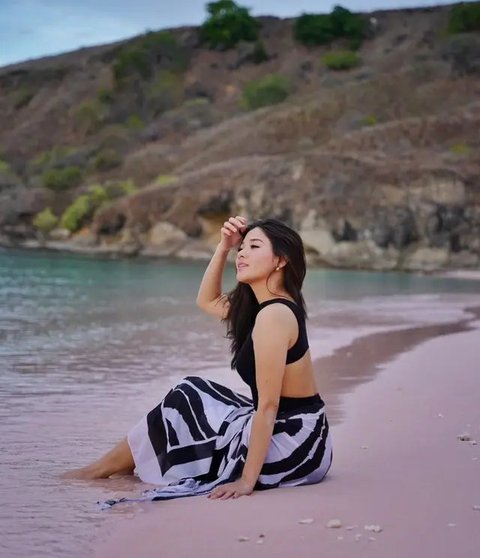 Di Pantai Pink, Naysilla Mirdad mengenakan swimsuit hitam yang dipadukan dengan kain putih berpolakan hitam. 