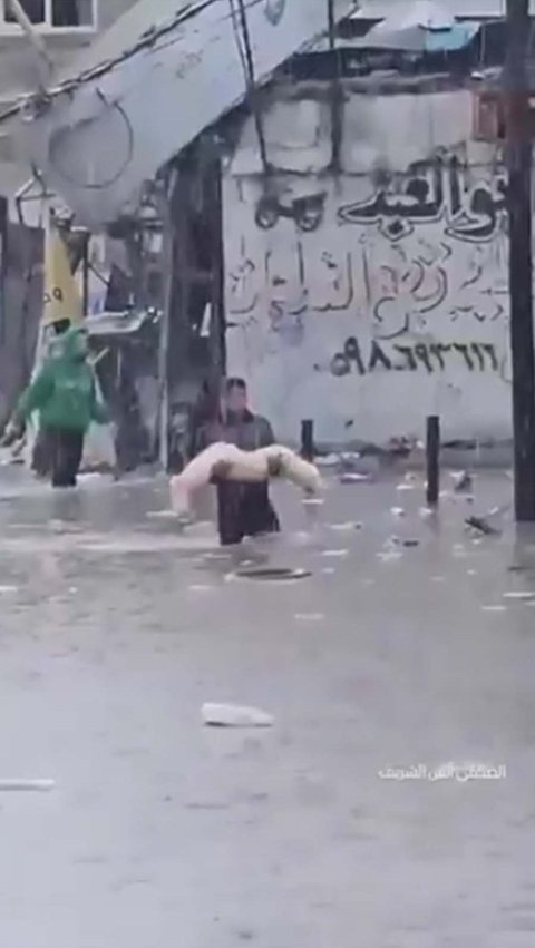 Video tersebut turut memperlihatkan sebuah pemandangan yang menyayat hati saat seorang pria Palestina menggendong jenazah yang terbungkus kain kafan putih di tengah banjir dan hujan deras.
