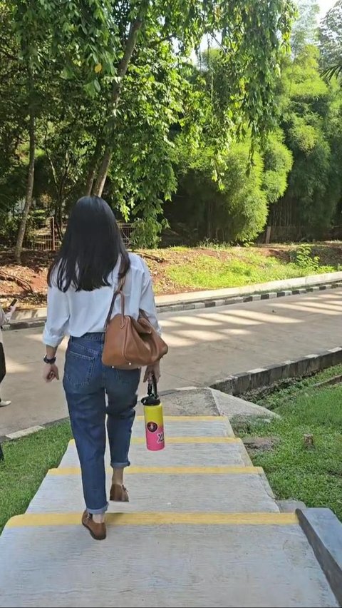 Dian is wearing a simple outfit, she also appears to be carrying a bag and a tumbler.