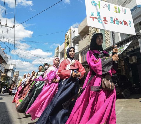 Sebuah foto yang diambil pada 14 Oktober 2023 menampilkan para peserta dengan pakaian adat Korea memegang papan petunjuk dengan tulisan Hangeul atau aksara Korea dalam sebuah parade untuk merayakan HUT Kota Baubau, Pulau Buton, Sulawesi Tenggara.