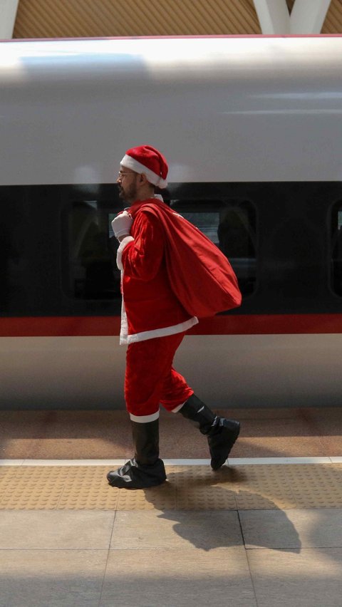 Petugas berkostum Sinterklas membawa hadiah untuk dibagikan kepada penumpang kereta cepat Whoosh di Stasiun Kereta Cepat Halim, Jakarta, Minggu (24/12/2023).