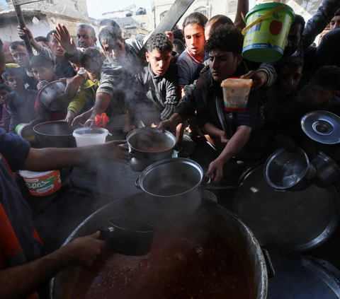 Warga Palestina berebut antrean untuk mendapatkan bagian makanan dari bantuan kemanusiaan di kamp pengungsi di Rafah, di selatan Jalur Gaza (2/12/2023).<br>