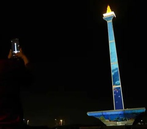 Pengunjung mengambil gambar video mapping dalam Monas Week 2023 di tugu Monumen Nasional (Monas), Jakarta Pusat, Jumat (29/12/2023). Penampilan video mapping di Monas ini hadir untuk memeriahkan libur Natal dan tahun baru.