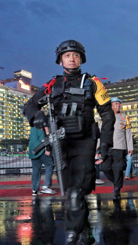 Personel Brimob dengan persenjataan lengkap saat berjaga di Bundaran HI, Jakarta, Minggu (31/12/2023).