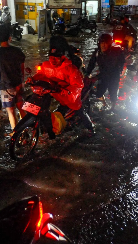 Mereka terpaksa turun untuk mendorong kendaraannya melintasi genangan banjir yang merendam jalan utama itu.