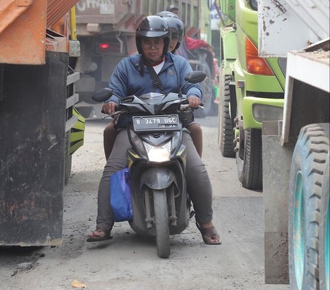 Pengendara sepeda motor melintas di antara truk tambang yang terjebak macet di Jalan Raya Parung Panjang, Bogor, Jawa Barat, Sabtu (9/12/2023).