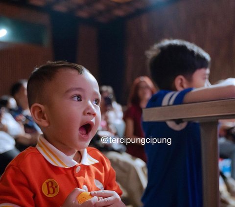 Ini potret Rayyanza saat ikut acara press conference Turnamen Olahraga Selebriti Indonesia. Balita yang akrab disapa Cipung ini tampak ditemani sang kakak, Rafathar. Cipung mengenakan jersey warna merah.