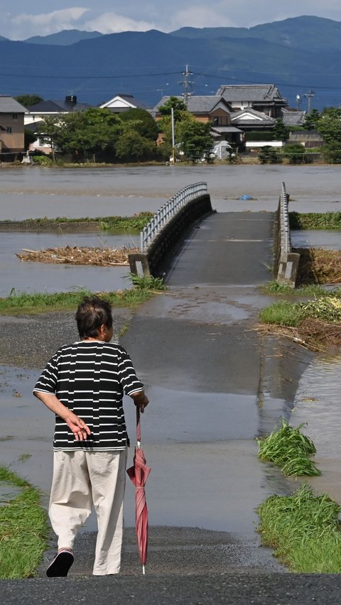 Seorang wanita melihat ke area yang tergenang air akibat luapan sungai di kota Tachiarai, prefektur Fukuoka, Senin (10/7/2023) setelah hujan lebat melanda wilayah Pulau Kyushu.