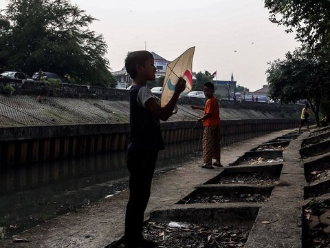 FOTO: Ruang Terbuka Hijau Minim, Anak-Anak di Jakarta Main Layang-Layang di Pinggir Kali