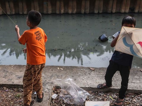 FOTO: Ruang Terbuka Hijau Minim, Anak-Anak di Jakarta Main Layang-Layang di Pinggir Kali