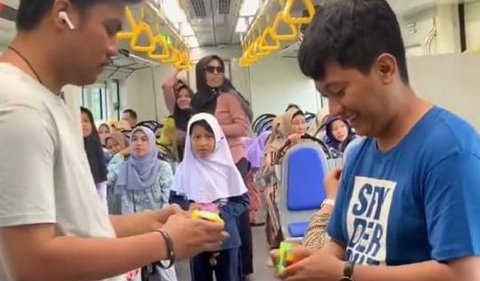 Tak hanya itu, terlihat ada juga yang asik main rubik di dalam kereta. Dua anak muda terlihat berdiri di lorong antar penumpang dan bertanding rubik. Pertandingan tersebut pun menarik perhatian anak-anak yang juga menjadi penumpang kereta.