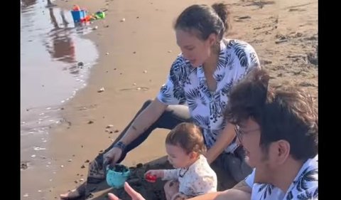 Potret Baby Djiwa tampak main pasir pantai. Tampak Nadine Chandrawinata ikut bermain bersama sang anak.