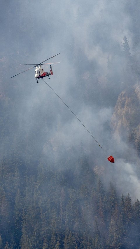 Api yang terus berkobar dengan asapnya yang pekat terpantau saat helikopter tengah melakukan upaya pemadam dari udara.