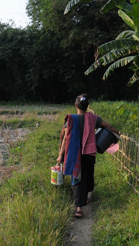 Warga saat membawa perlengkapan cuci, pakaian dan mandi saat akan menuju ke aliran Kali Cihoe di Cibarusah, Kabupaten Bekasi, Rabu (19/7/2023).